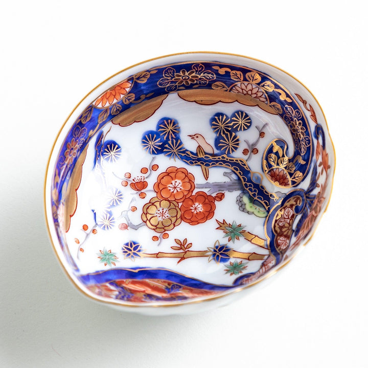 A small, triangular-shaped condiment bowl with intricate red, blue, and gold patterns featuring floral and geometric designs.