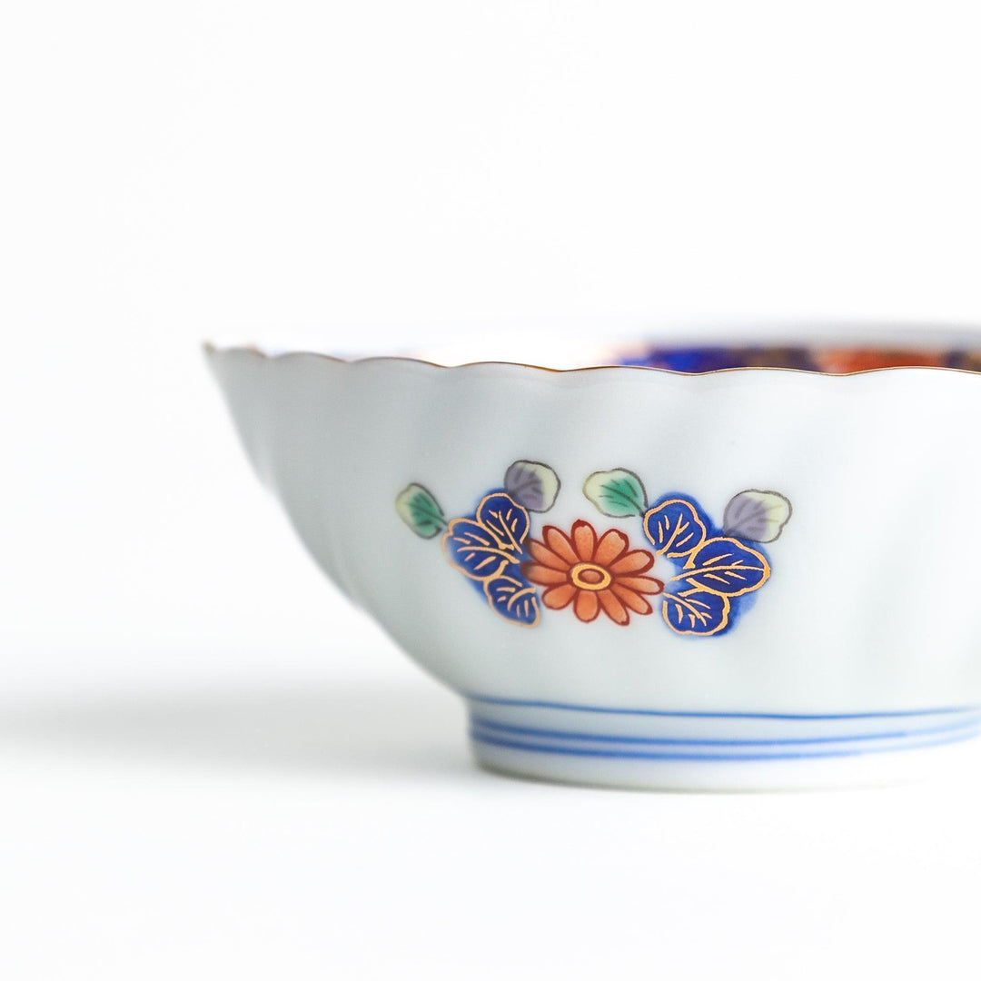 A small, triangular-shaped condiment bowl with intricate red, blue, and gold patterns featuring floral and geometric designs.