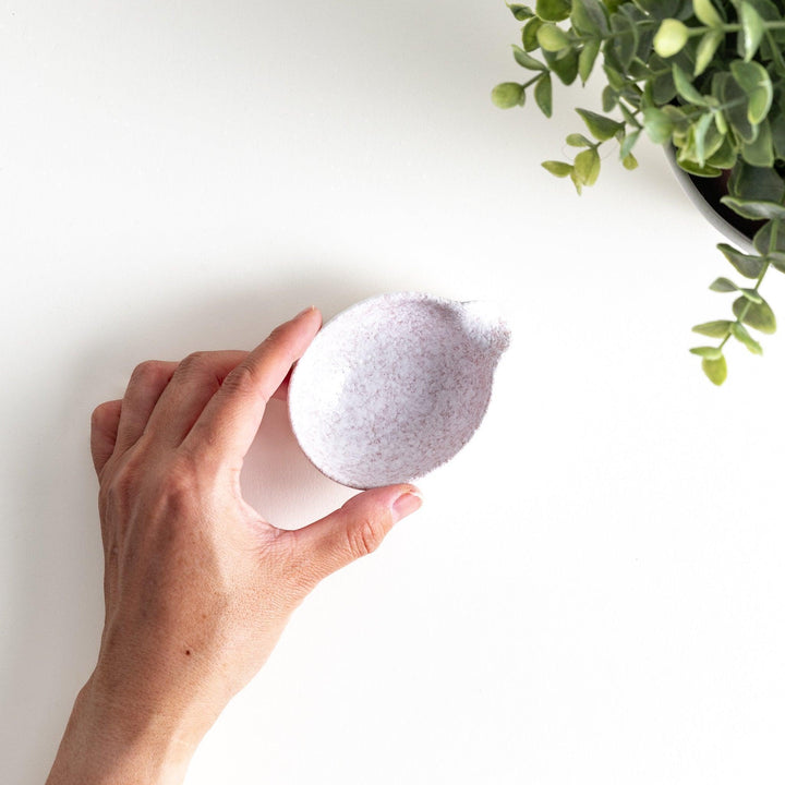 A condiment bowl with a soft pink speckled texture and a pouring spout.