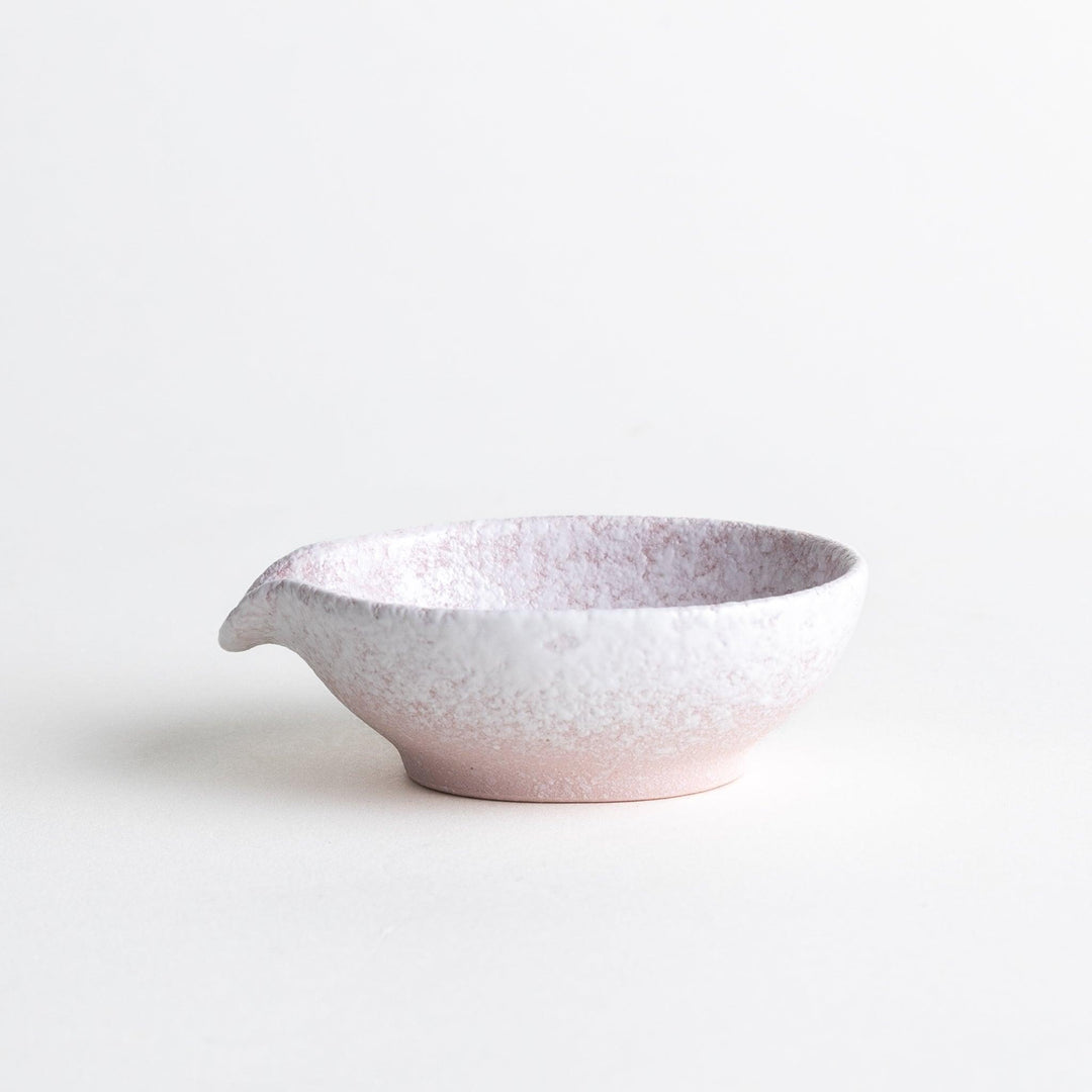 A condiment bowl with a soft pink speckled texture and a pouring spout.