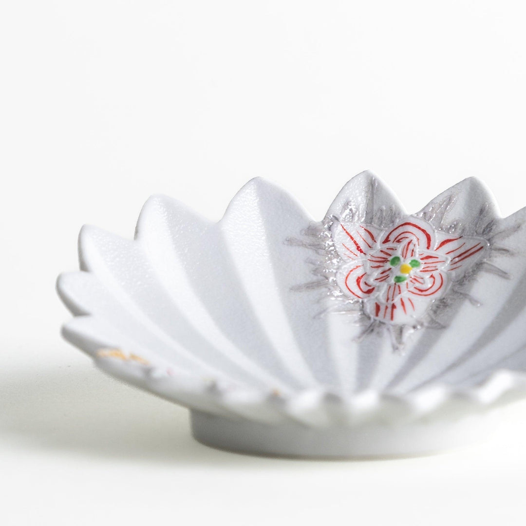 A white, leaf-shaped ceramic plate with delicate pink and gold floral decorations.