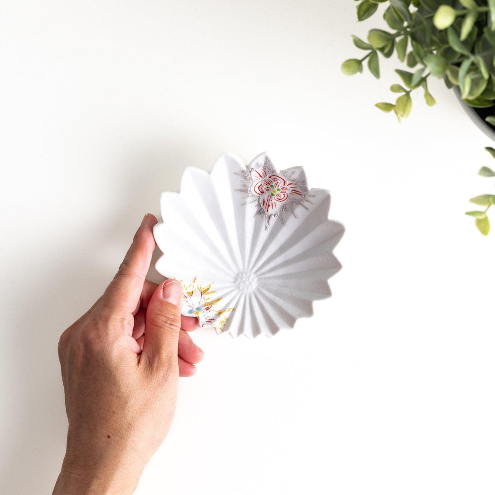 A white, leaf-shaped ceramic plate with delicate pink and gold floral decorations.