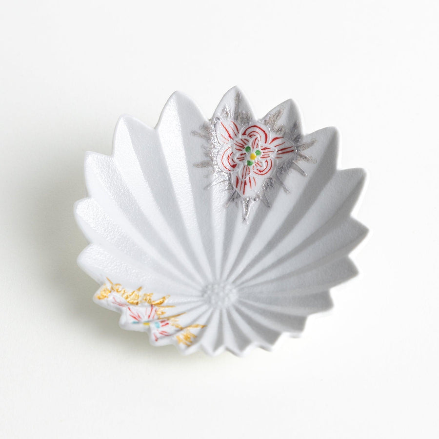 A white, leaf-shaped ceramic plate with delicate pink and gold floral decorations.