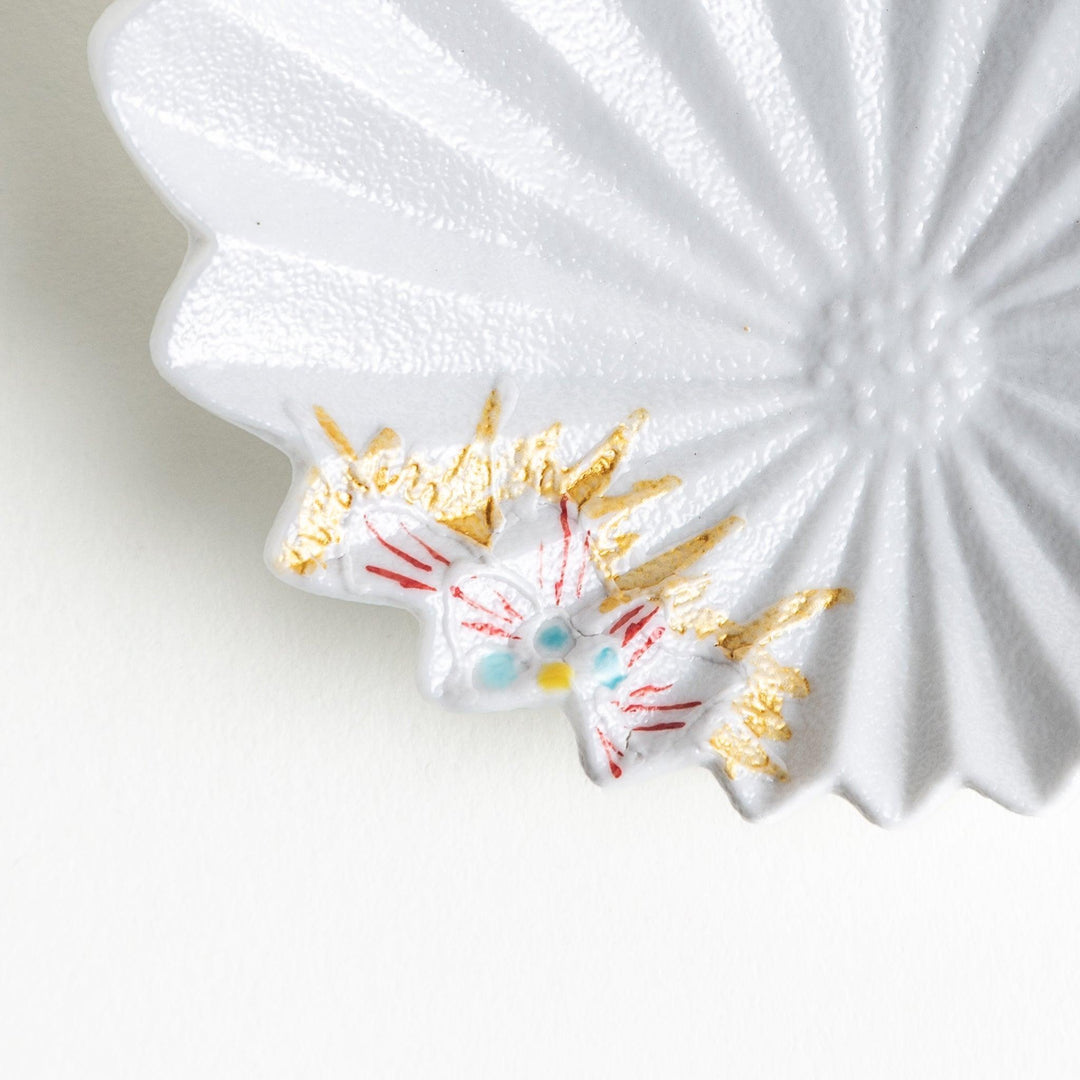 A white, leaf-shaped ceramic plate with delicate pink and gold floral decorations.