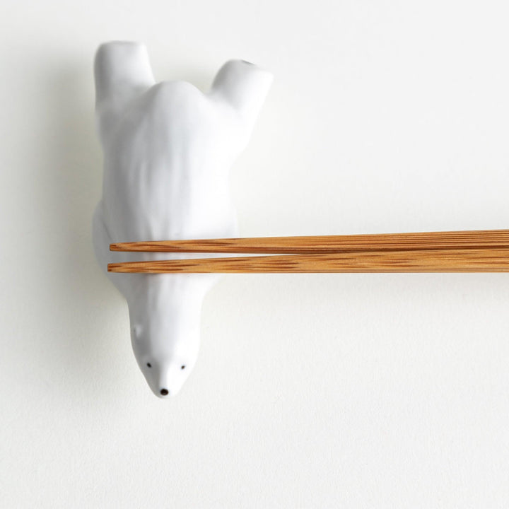 A smooth, white ceramic chopstick rest shaped like a polar bear.