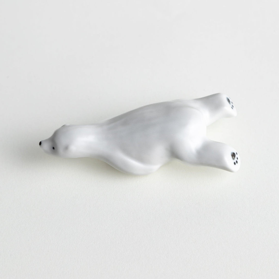 A smooth, white ceramic chopstick rest shaped like a polar bear.