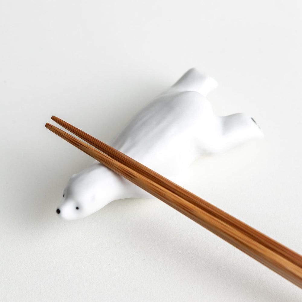 A smooth, white ceramic chopstick rest shaped like a polar bear.