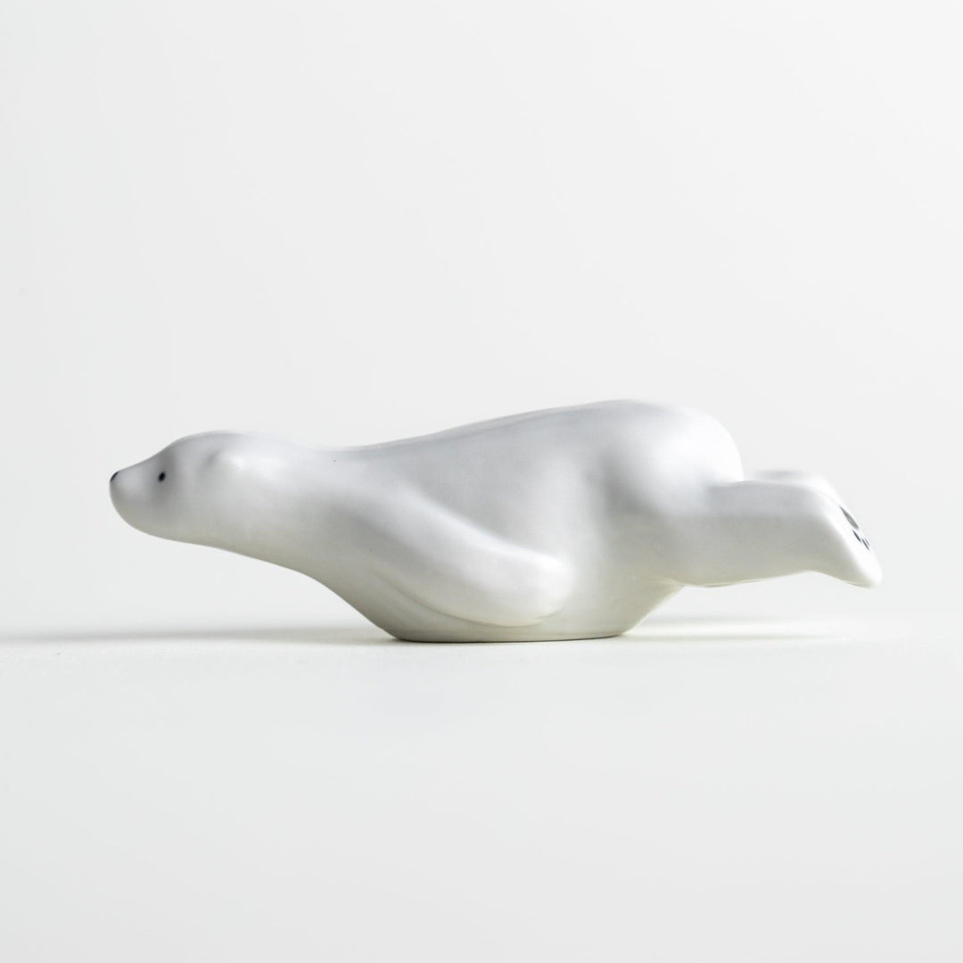 A smooth, white ceramic chopstick rest shaped like a polar bear.