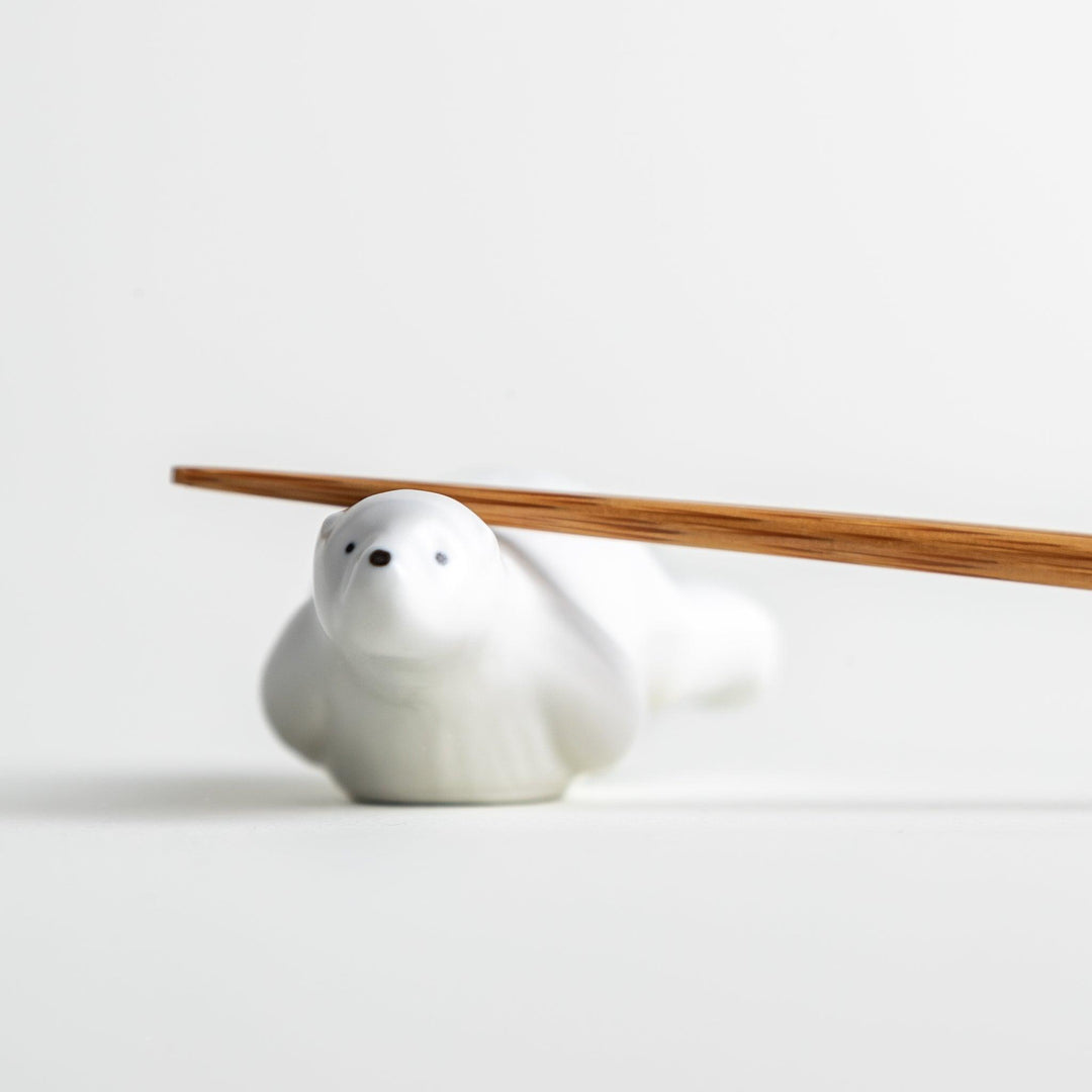 A smooth, white ceramic chopstick rest shaped like a polar bear.