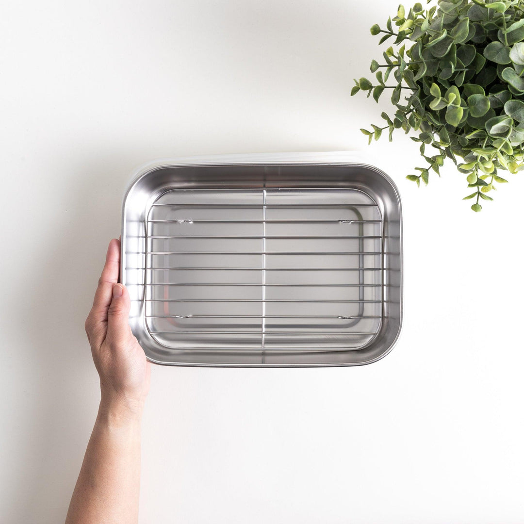 Rectangular stainless steel food prep trays with a wire rack and a white plastic lid.