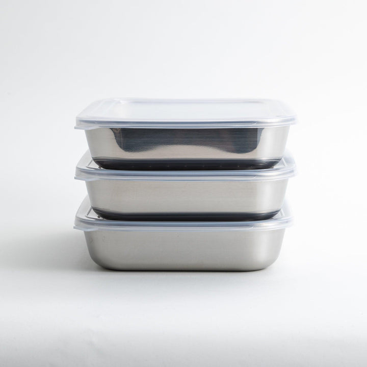 Rectangular stainless steel food prep trays with a wire rack and a white plastic lid.