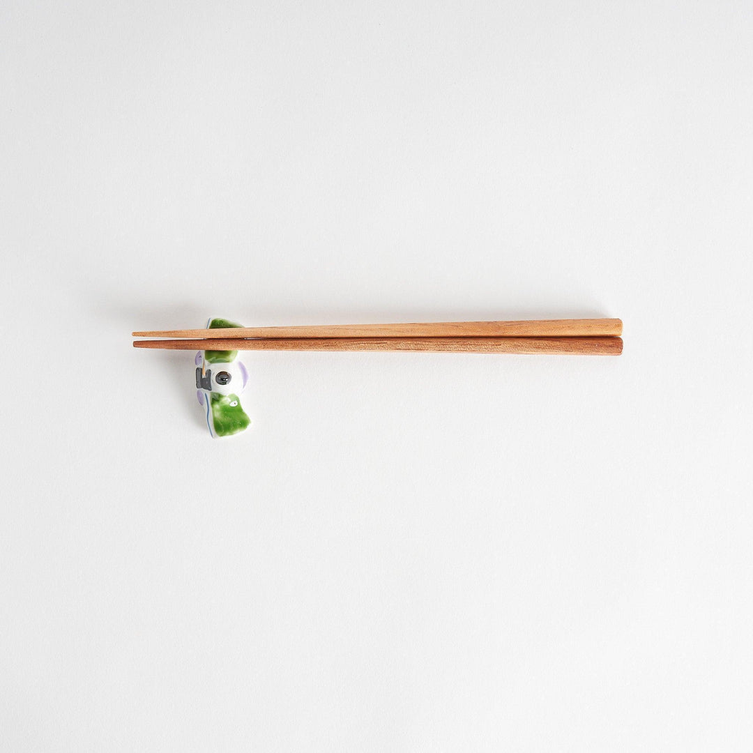 A ceramic chopstick rest shaped like a Japanese prince, painted in orange with floral accents.