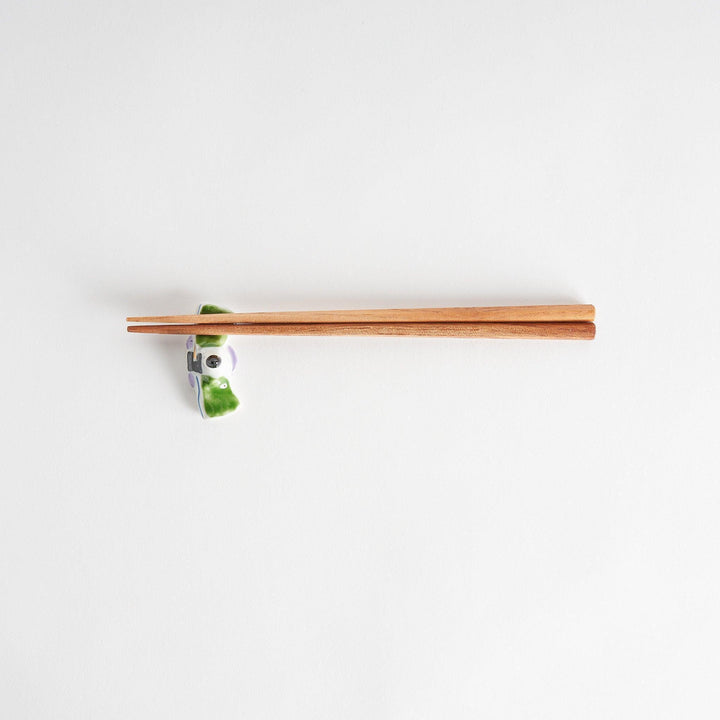 A ceramic chopstick rest shaped like a Japanese prince, painted in orange with floral accents.