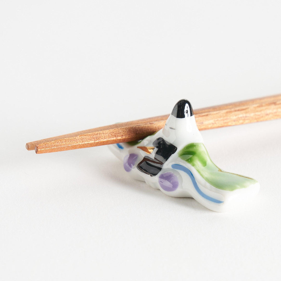 A ceramic chopstick rest shaped like a Japanese prince, painted in orange with floral accents.