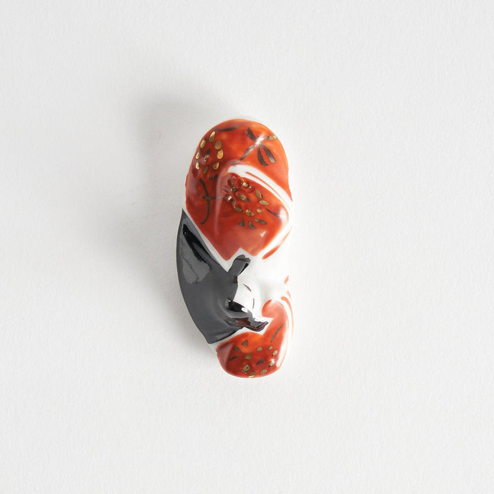 A ceramic chopstick rest shaped like a Japanese princess, painted in orange with floral accents.