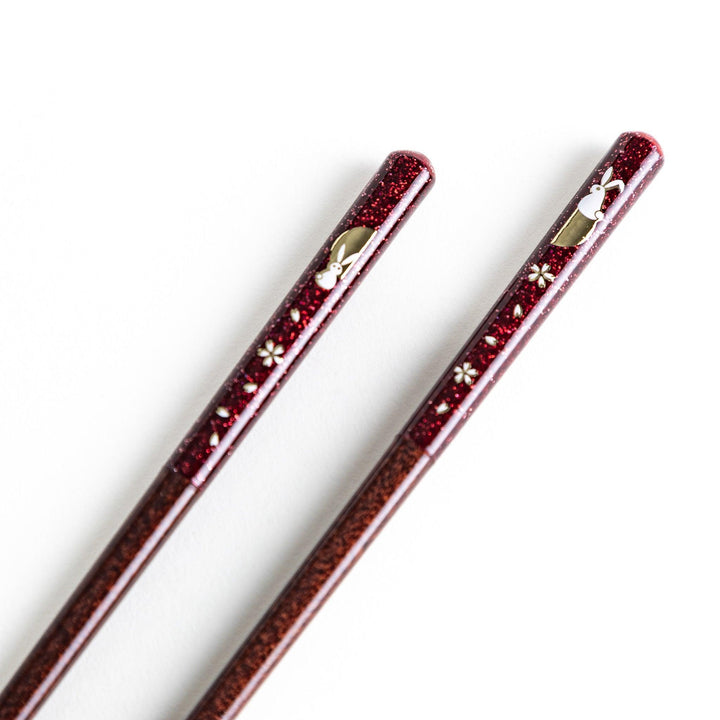 A pair of lacquered chopsticks adorned with floral patterns and rabbit. Available in purple or red.