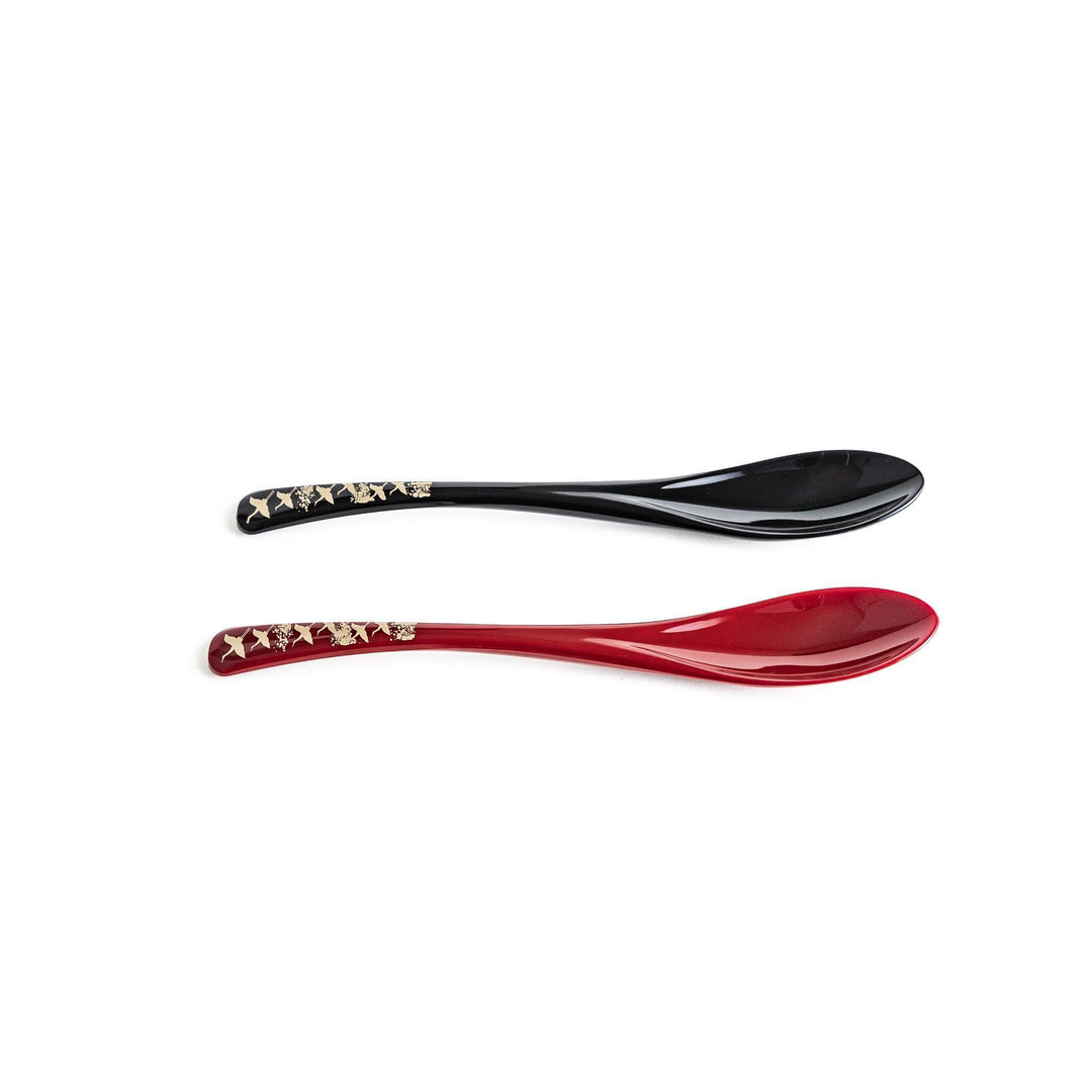 A boxed set of two lacquered spoons, one red and one black, featuring a crane pattern in gold on the handles.