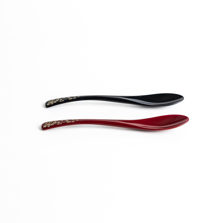 A boxed set of two lacquered spoons, one red and one black, each with gold sakura patterns on the handles.