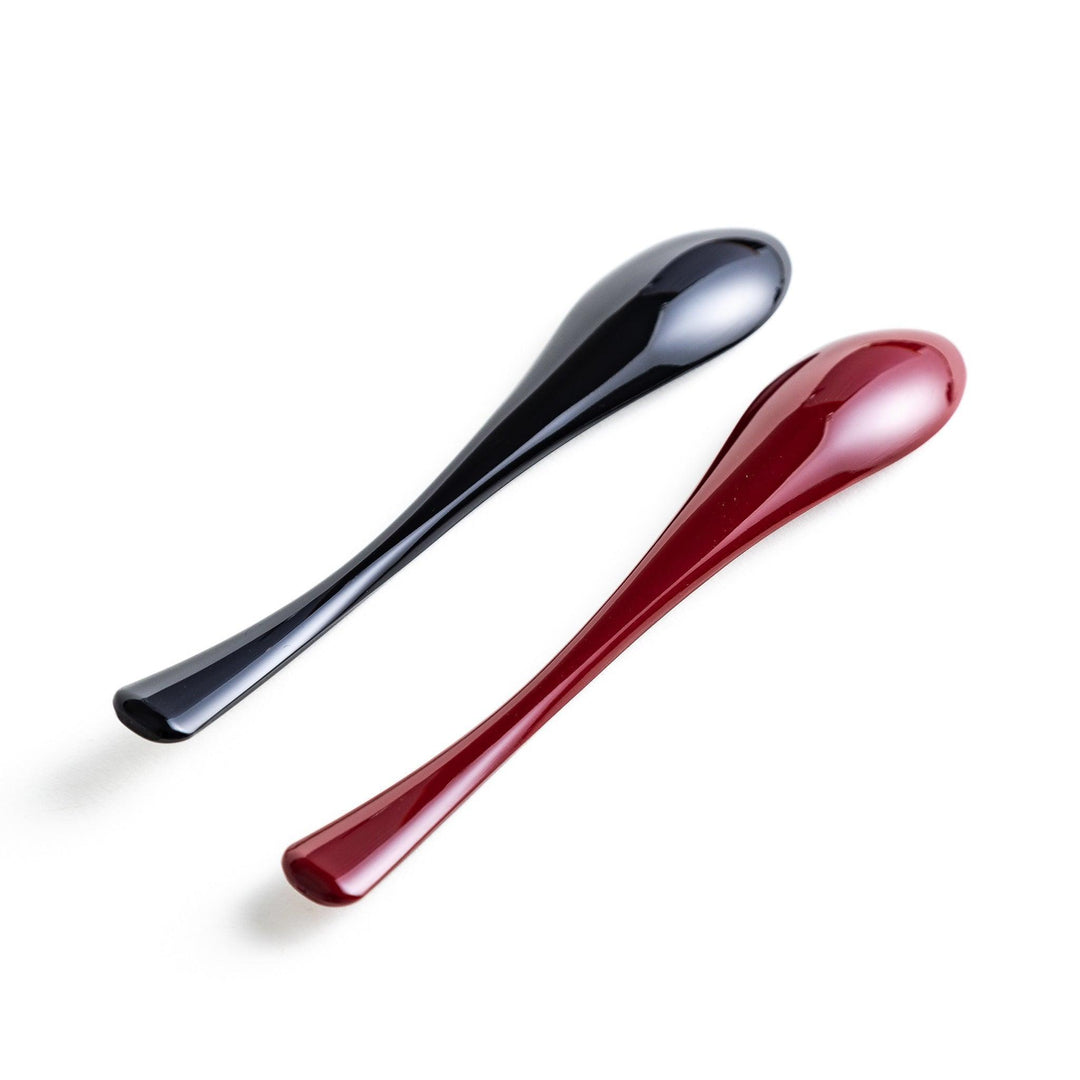 A boxed set of two lacquered spoons, one red and one black, each with gold sakura patterns on the handles.