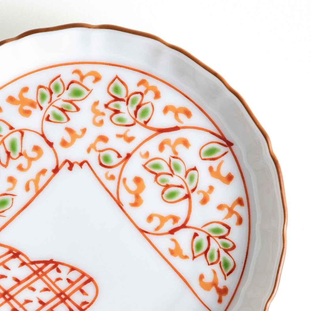 A ceramic plate decorated with an orange and green floral motif, with Mount Fuji in the center, bordered by a gold rim.