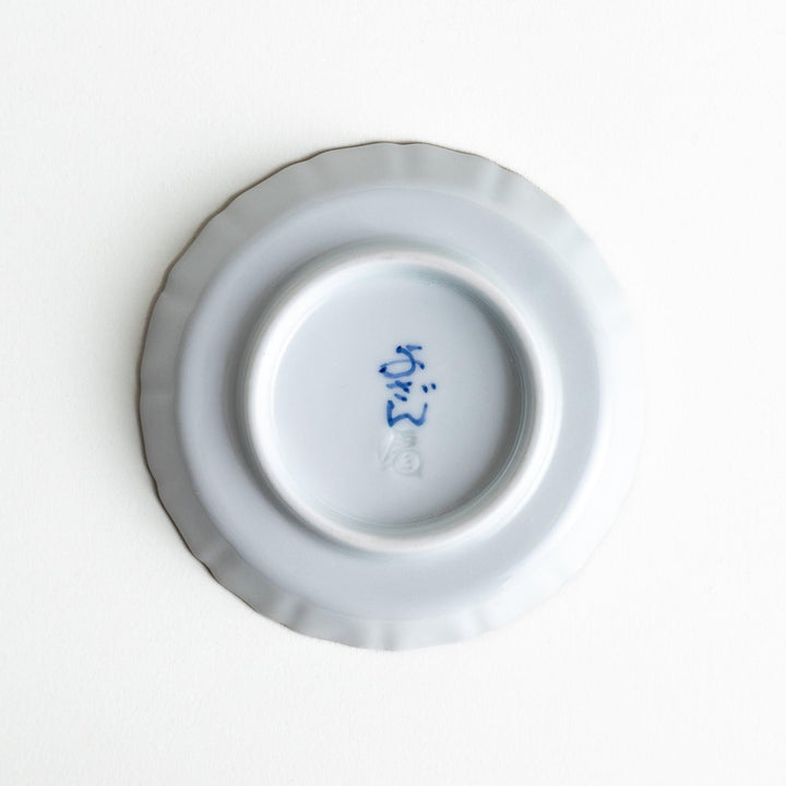 A ceramic plate decorated with an orange and green floral motif, with Mount Fuji in the center, bordered by a gold rim.