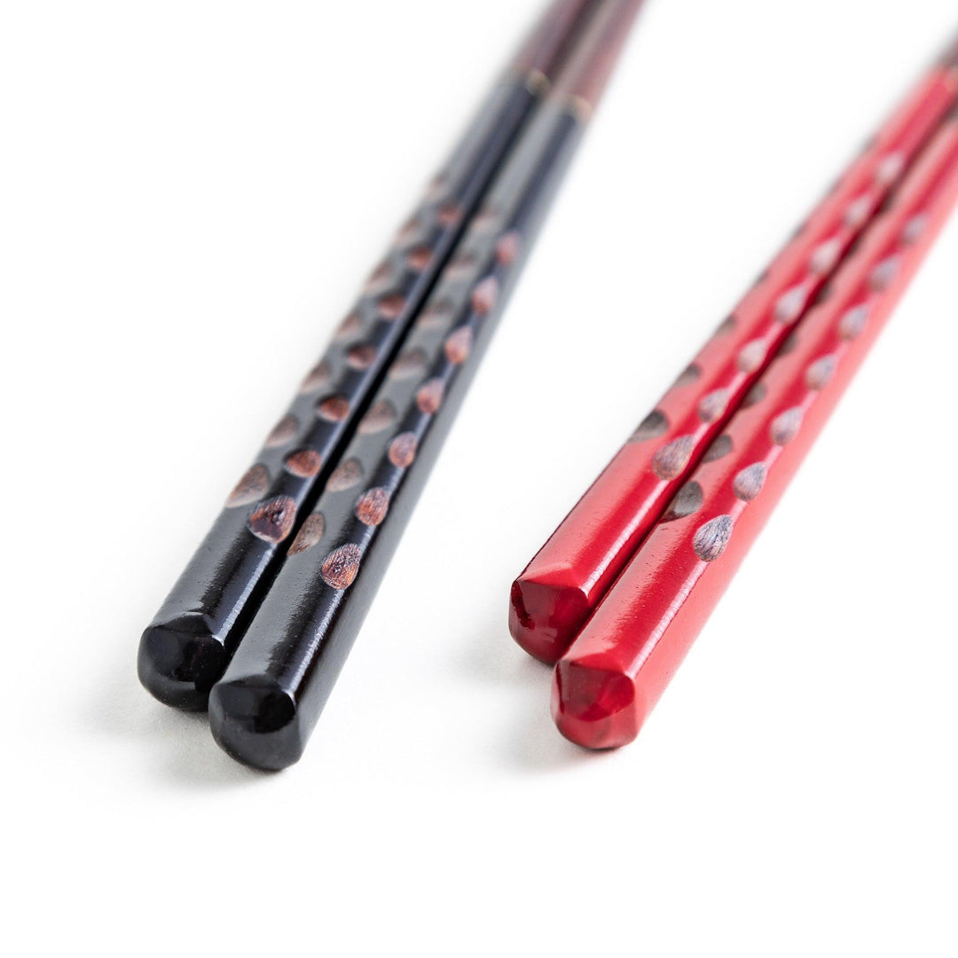 A boxed set of two pairs of chopsticks, one with black and one with red handles, both featuring textured grips.