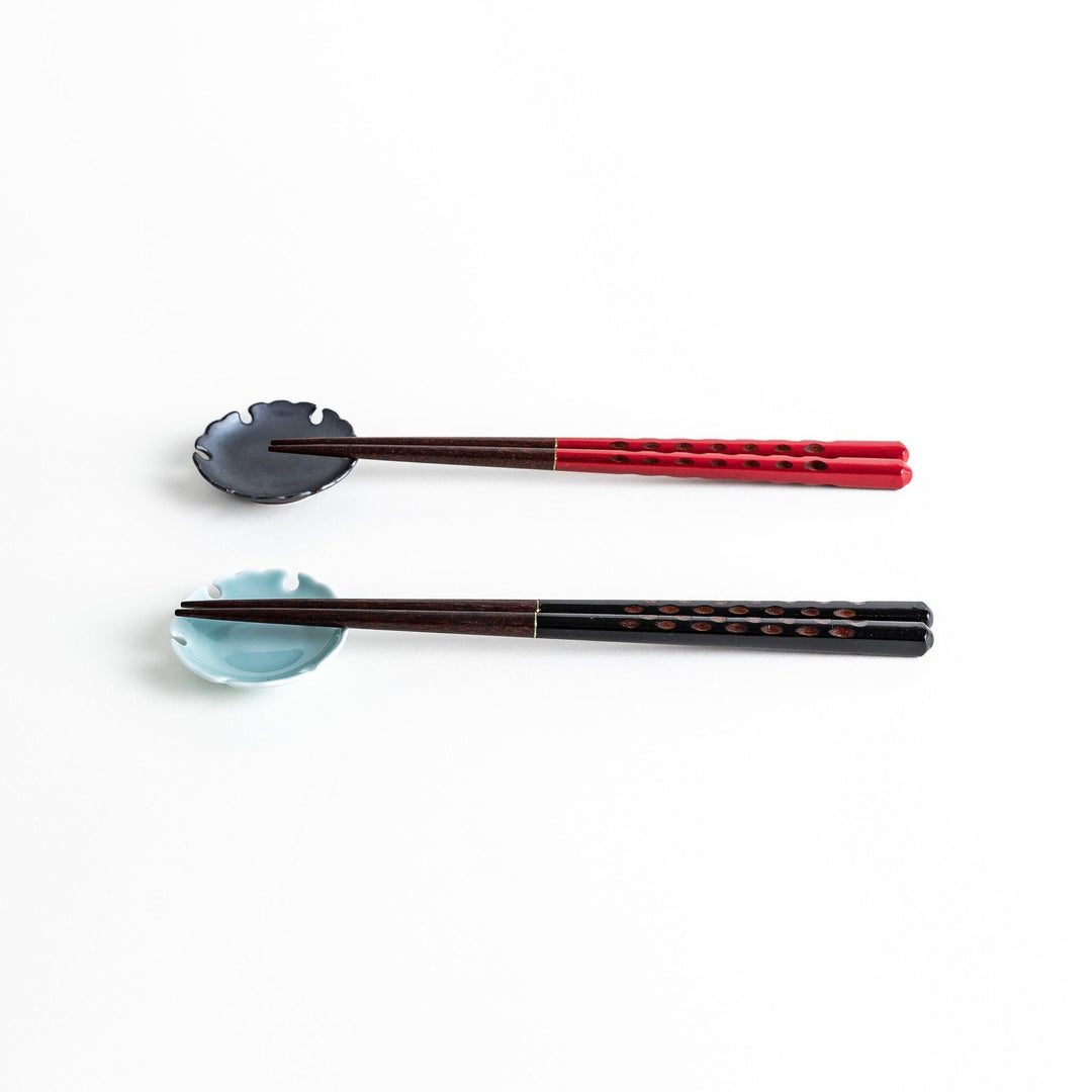 A boxed set of two pairs of chopsticks, one with black and one with red handles, both featuring textured grips.