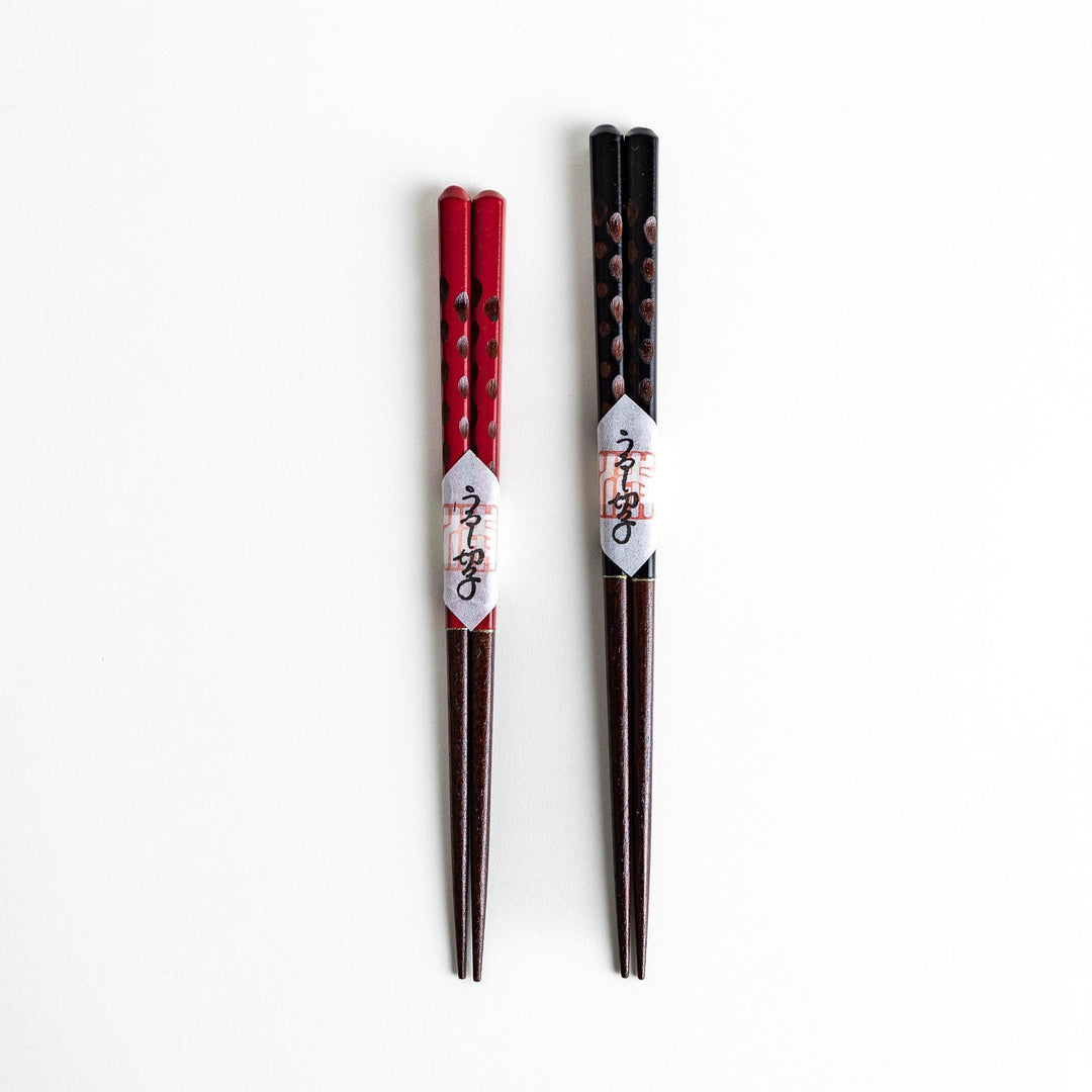 A boxed set of two pairs of chopsticks, one with black and one with red handles, both featuring textured grips.