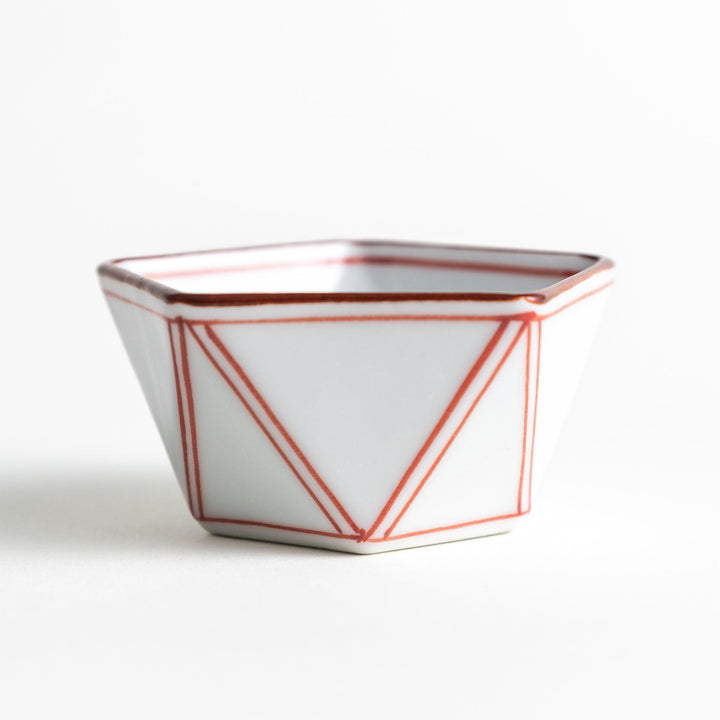 A small, white pentagonal bowl featuring red geometric lines and a brown rim.