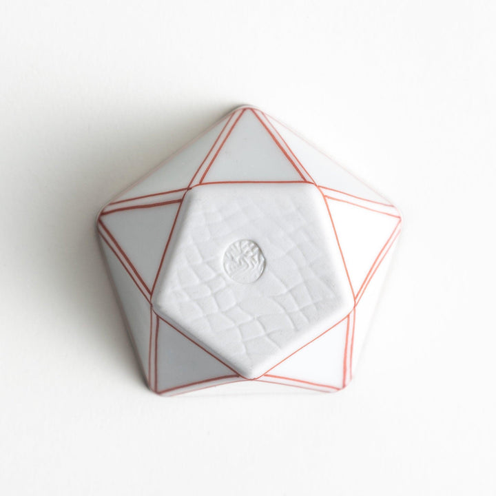 A small, white pentagonal bowl featuring red geometric lines and a brown rim.