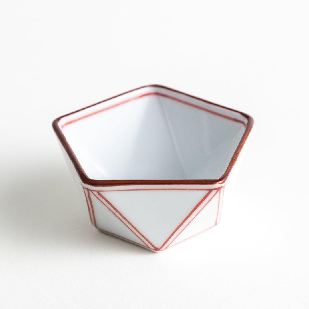 A small, white pentagonal bowl featuring red geometric lines and a brown rim.