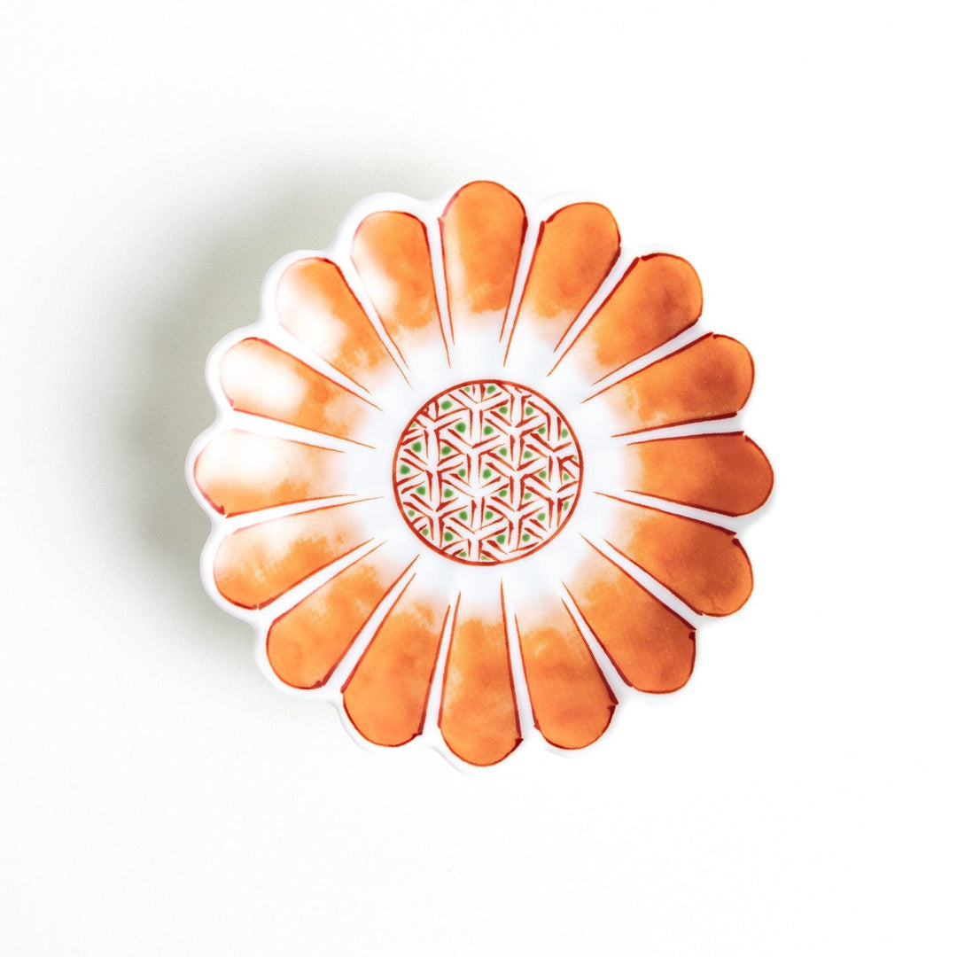 A small, scalloped-edge porcelain dish with orange chrysanthemum petal designs and a geometric center.