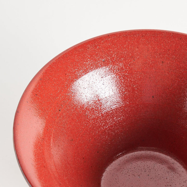 A red ramen bowl with black horizontal lines engraved around its exterior.