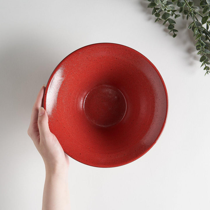 A red ramen bowl with black horizontal lines engraved around its exterior.