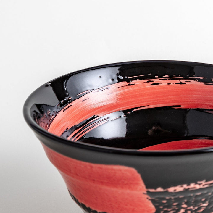 A black ramen bowl with a wide red brushstroke across its exterior.