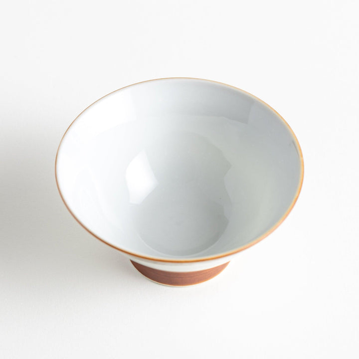 A white ceramic bowl decorated with a blue floral pattern around the rim and a brown base.