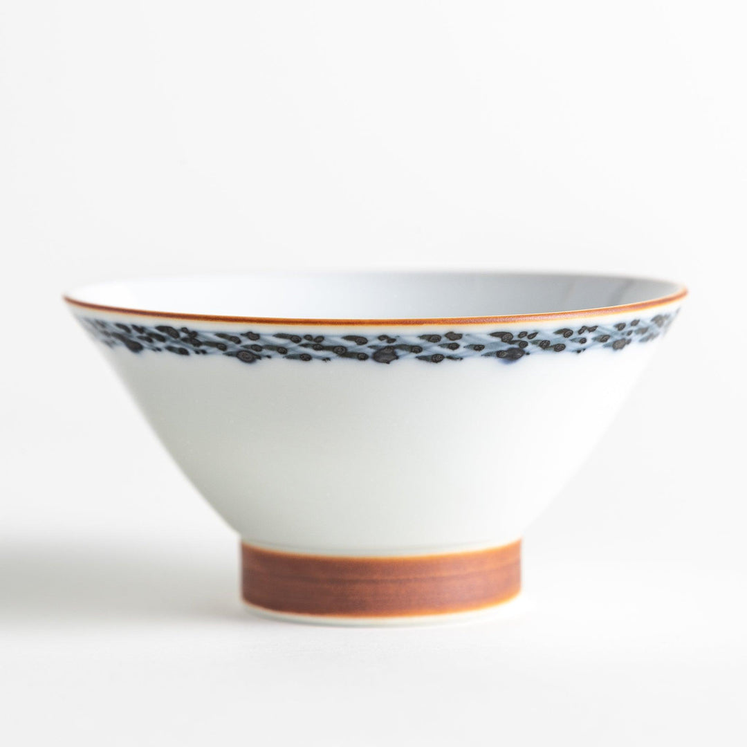 A white ceramic bowl decorated with a blue floral pattern around the rim and a brown base.