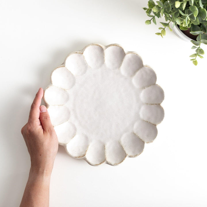 White ceramic dinner plates with scalloped flower-petal edges, available in black or white.