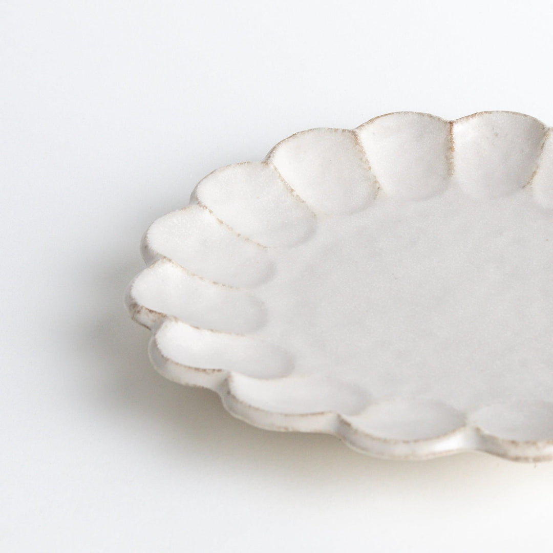 White ceramic dinner plates with scalloped flower-petal edges, available in black or white.