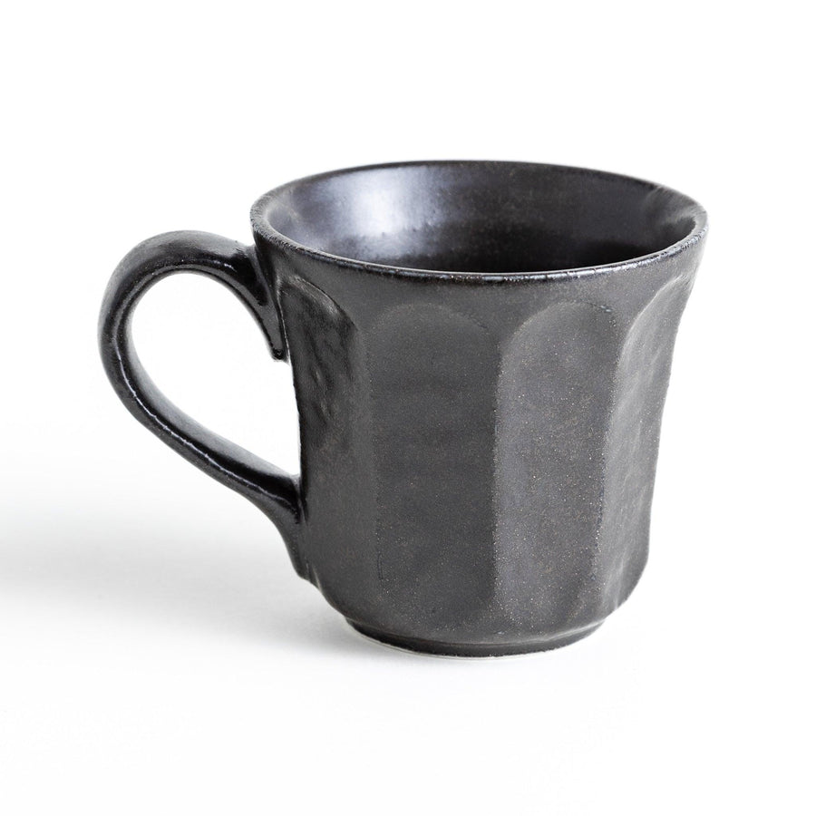 A minimalist ceramic mug with a textured, faceted finish. Available in black or white.