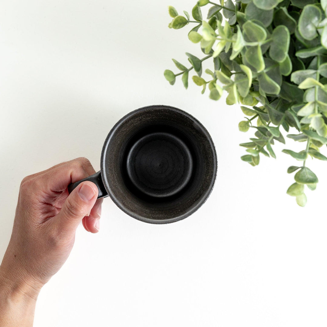 A minimalist ceramic mug with a textured, faceted finish. Available in black or white.