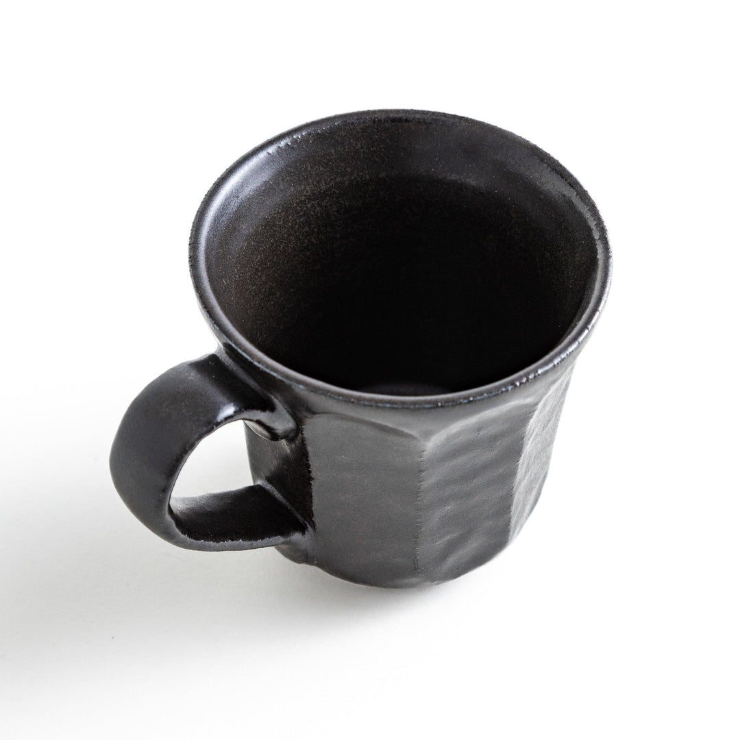 A minimalist ceramic mug with a textured, faceted finish. Available in black or white.