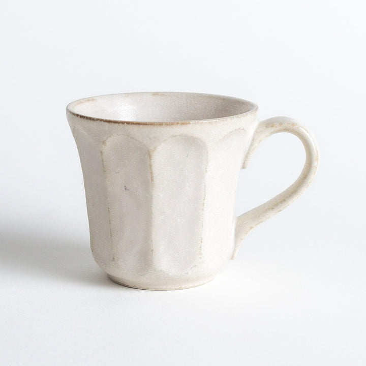 A minimalist ceramic mug with a textured, faceted finish. Available in black or white.