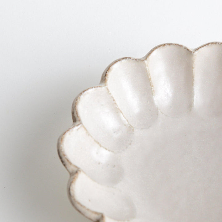 A white ceramic pasta bowl with a scalloped flower-petal design.