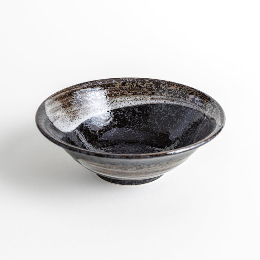 A deep ceramic bowl with a glossy black glaze and irregular brown and speckles.