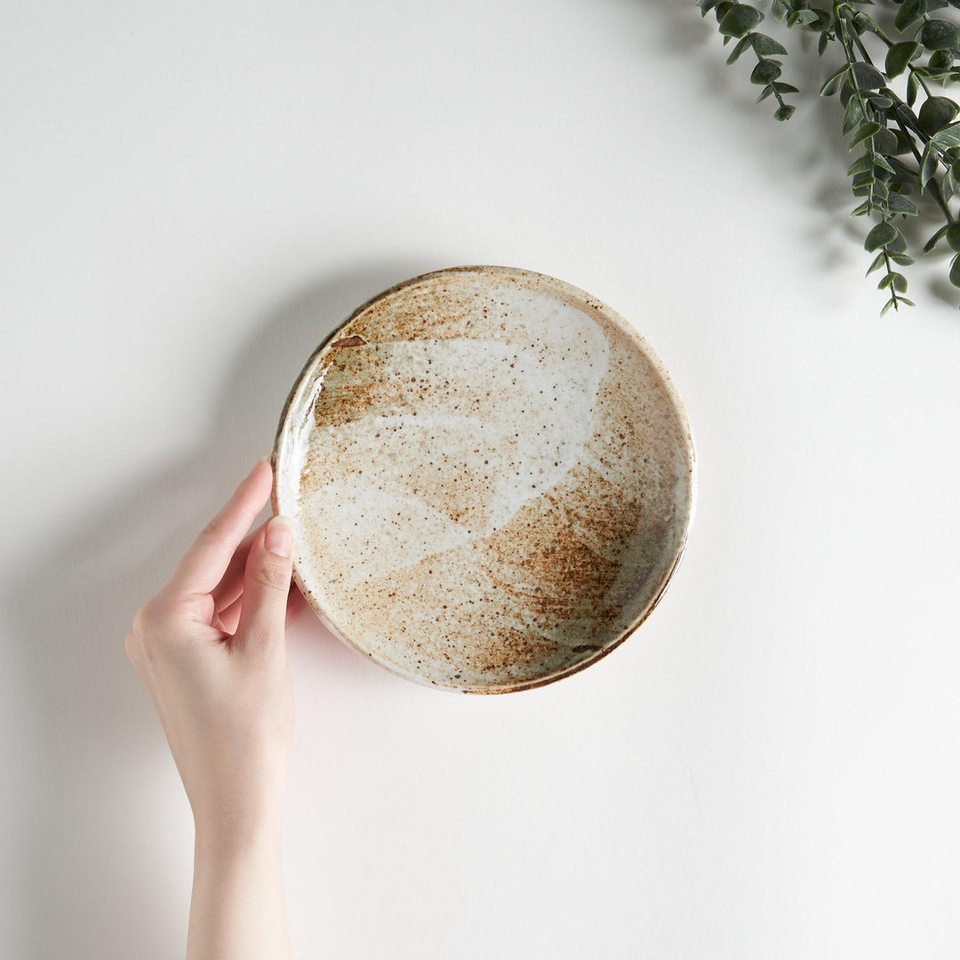 A small dessert plate with a speckled cream and brown glaze, featuring an organic, earthy design.