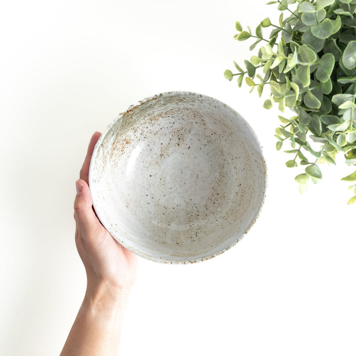 A ceramic bowl with a speckled cream and brown glaze, showcasing an earthy and organic finish.