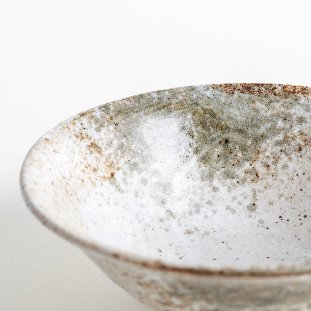 A large bowl with a speckled cream and brown glaze, featuring an organic, earthy design.