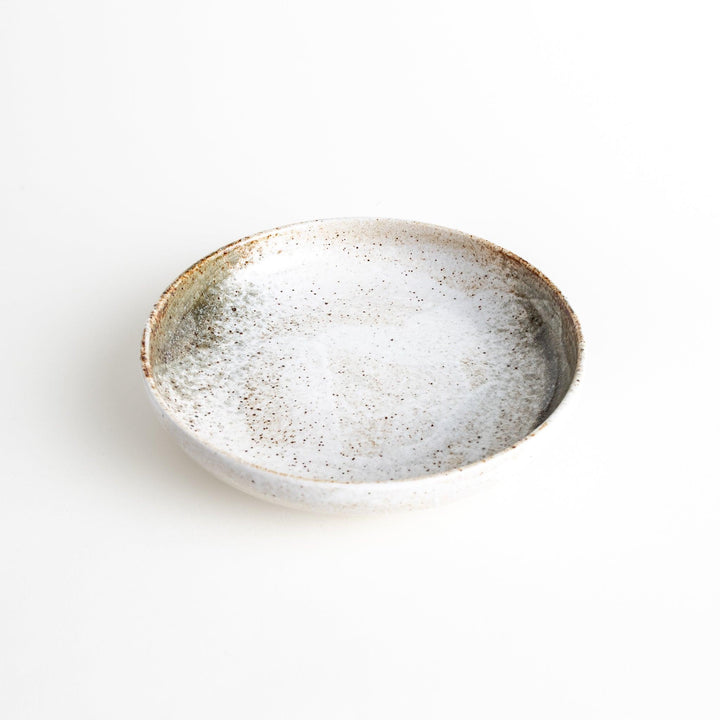 A pasta bowl with a speckled cream and brown glaze, displaying an earthy, organic design.