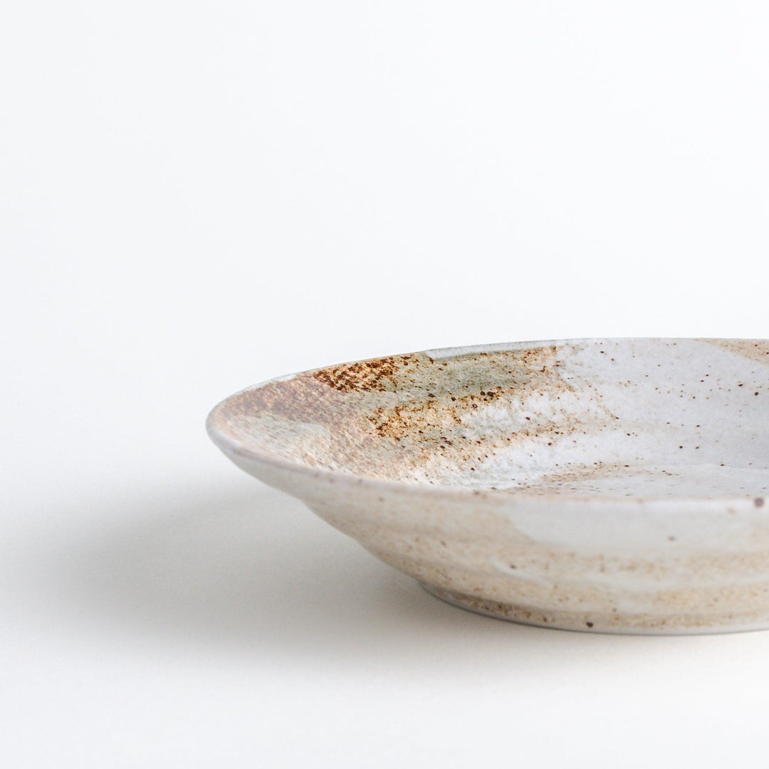 A salad plate with a speckled cream and brown glaze, featuring an earthy, organic design.